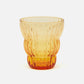A translucent amber-colored glass tumbler with a ribbed, textured design, shown on a clean white background.
