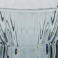 Close-up of a clear glass container or vase with a flared rim and vertically ribbed, wavy patterned glass.