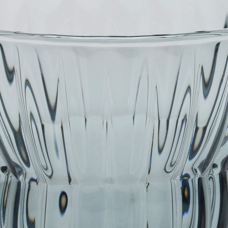 Close-up of a clear glass container or vase with a flared rim and vertically ribbed, wavy patterned glass.