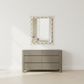 Gray dresser with gold-framed mirror on a white wall