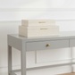 Stack of beige boxes on a gray console table with a white wall background