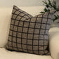 Grid-patterned pillow on a white sofa with a plant in the background