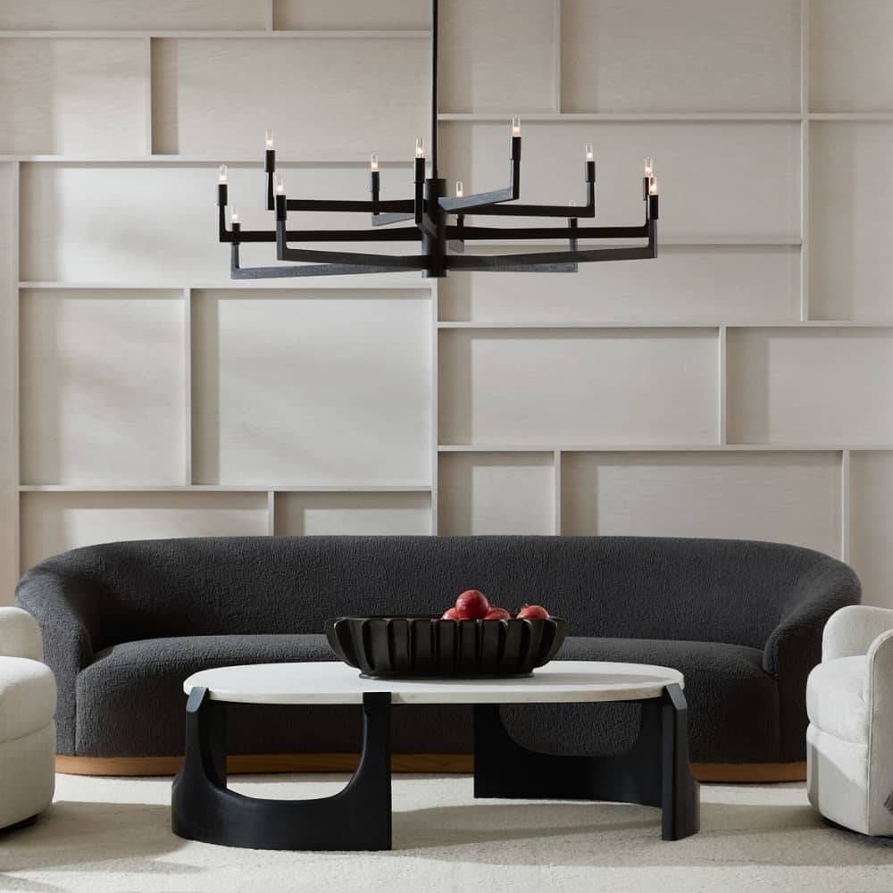 Modern living room with a black sofa, white coffee table, and decorative wall lights.
