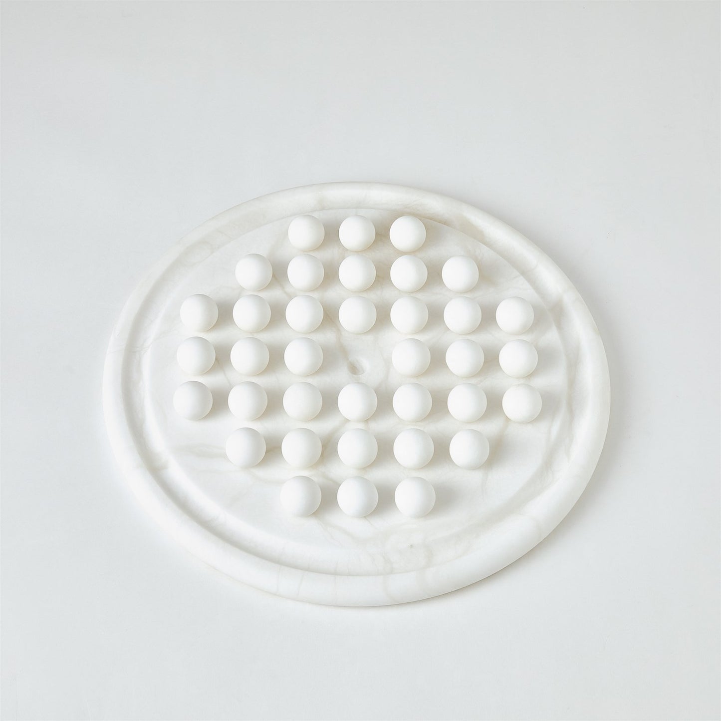 Round white marble trivet with circular pattern on a light gray background