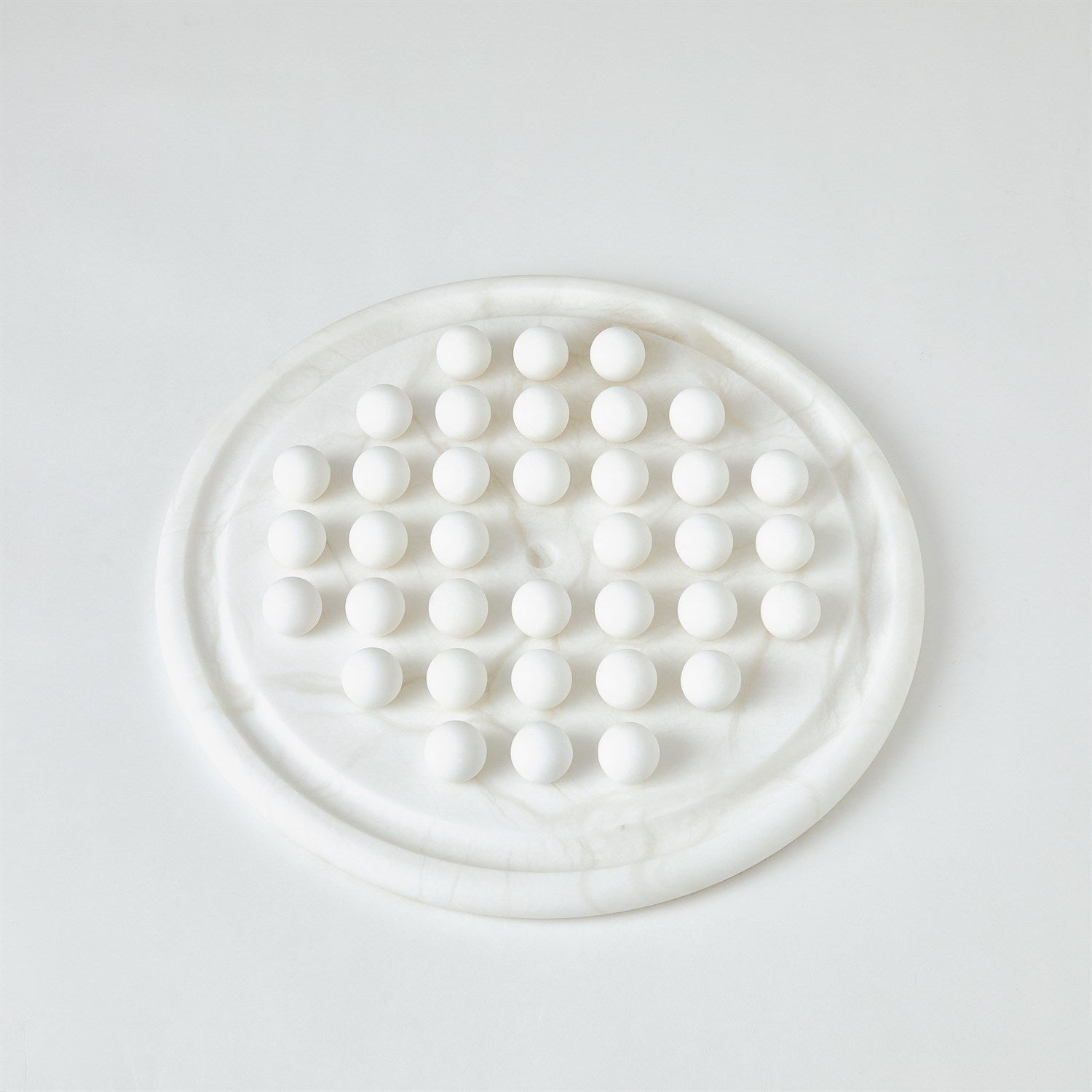 Round white marble trivet with circular pattern on a light gray background