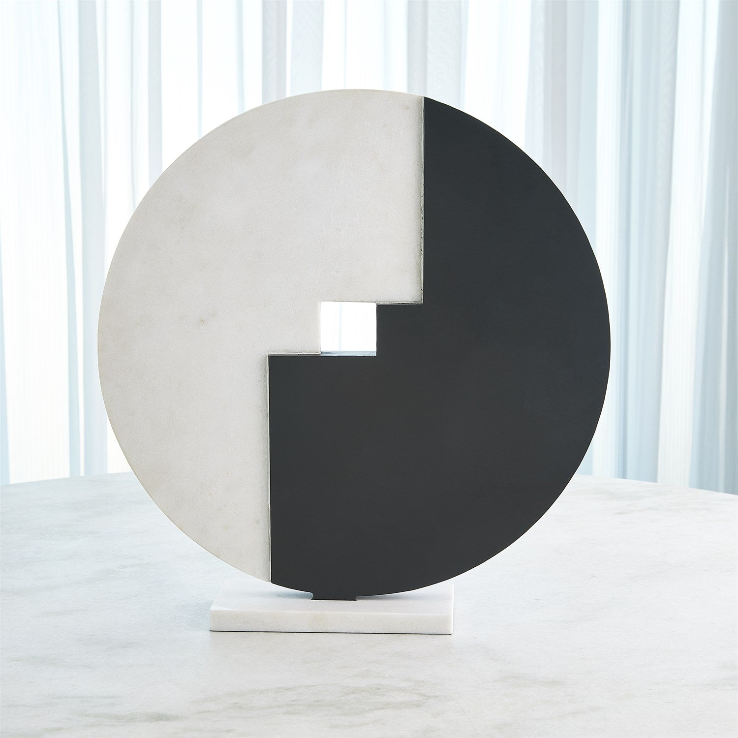 Abstract sculpture with a black and white circular design on a white background