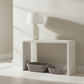 White shelf with two woven baskets and a white lamp against a light gray wall.(harlow and henritta)