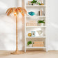 Palm tree floor lamp next to a white bookshelf with decorative items