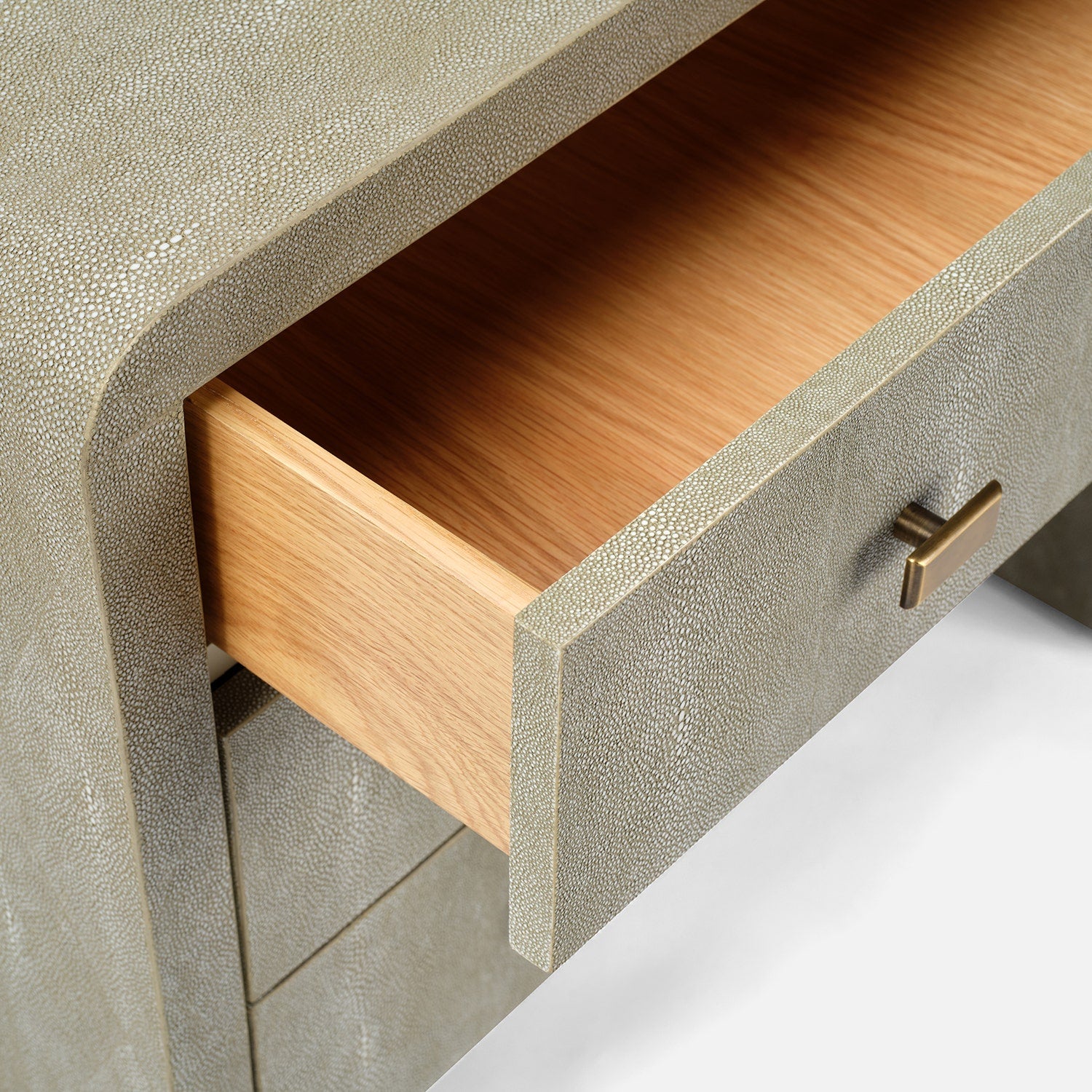 Close-up of a textured gray cabinet with an open wooden drawer and brass handle.