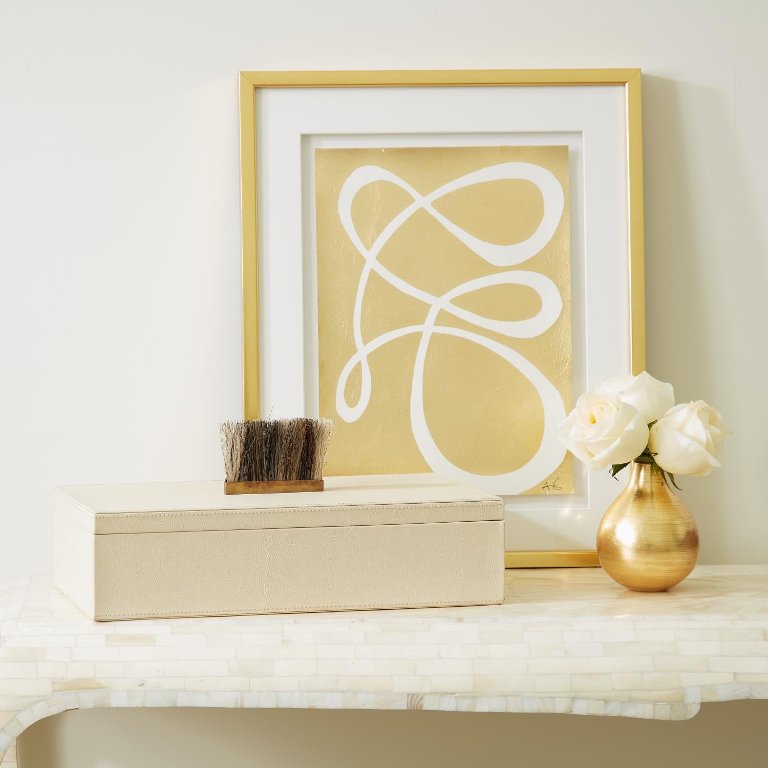 Framed abstract artwork on a shelf with decorative items