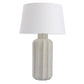 Table lamp with textured base and white shade on a white background
