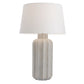 Table lamp with textured ceramic base and white shade on a white background