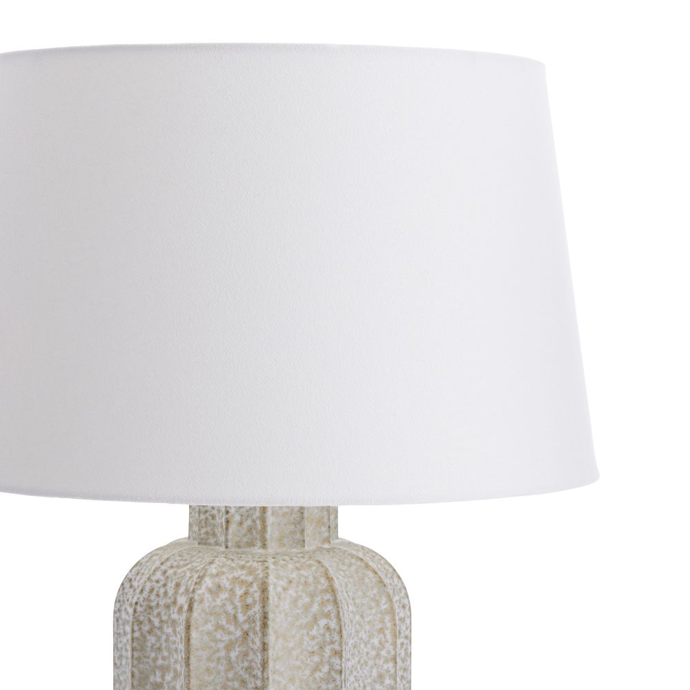 Table lamp with textured base and white shade on a white background