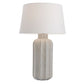 Table lamp with textured ceramic base and white shade on a white background