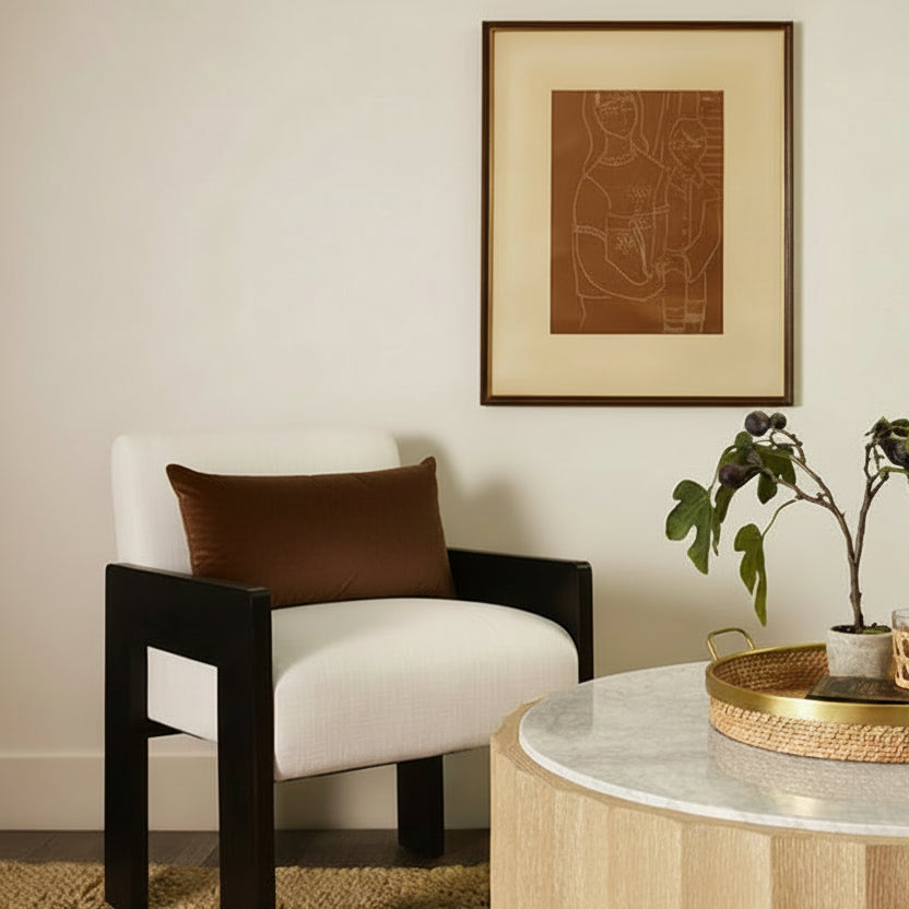 Modern armchair with a brown pillow in a living room setting.