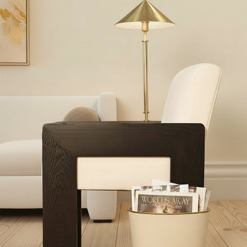 Modern living room with a white chair, black side table, and gold lamp.