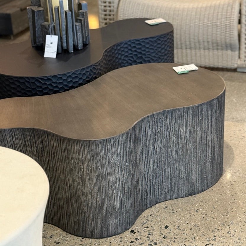 Modern outdoor furniture set with wicker chairs and a unique shaped table in an indoor setting.