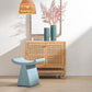 Light blue stool in front of a wooden cabinet with decorative elements.