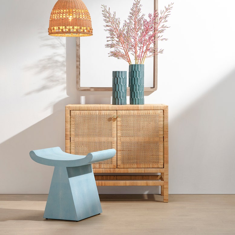 Light blue stool in front of a wooden cabinet with decorative elements.