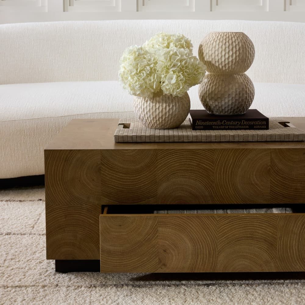 Wooden coffee table with decorative items including a vase of flowers and textured balls on a neutral background.