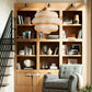 Living room with wooden bookshelf, gray armchair, and decorative items.
