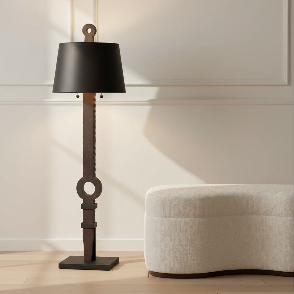 Floor lamp with black shade and decorative base in a room with a white wall and beige sofa.