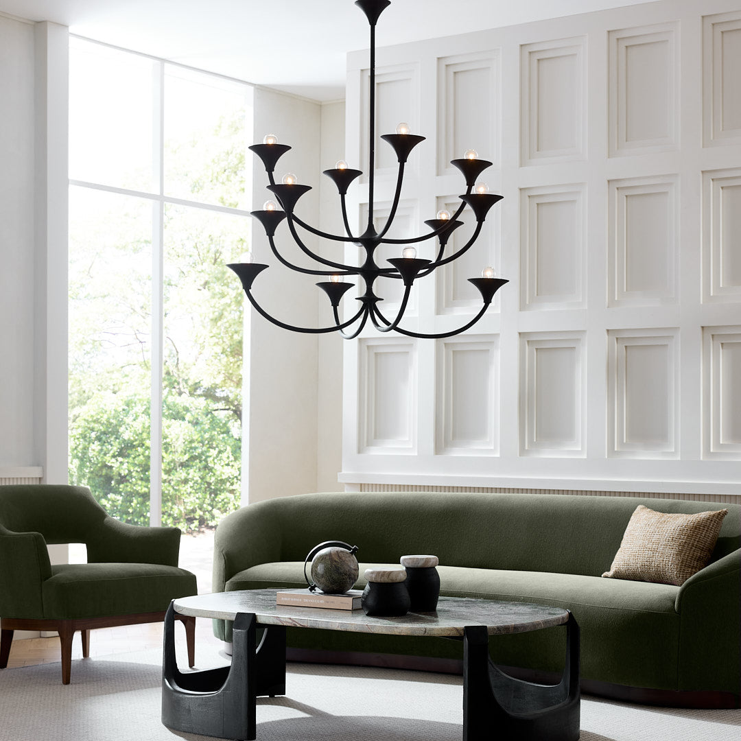 Modern living room with a green sofa, black coffee table, and chandelier.