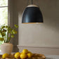 Black pendant light fixture in a room with a vase of flowers and fruit on a table.