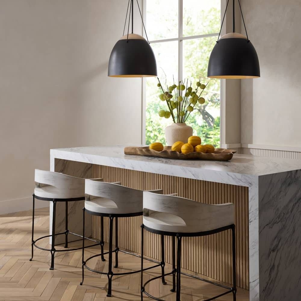 Modern kitchen island with marble countertop, stools, and black pendant lights.