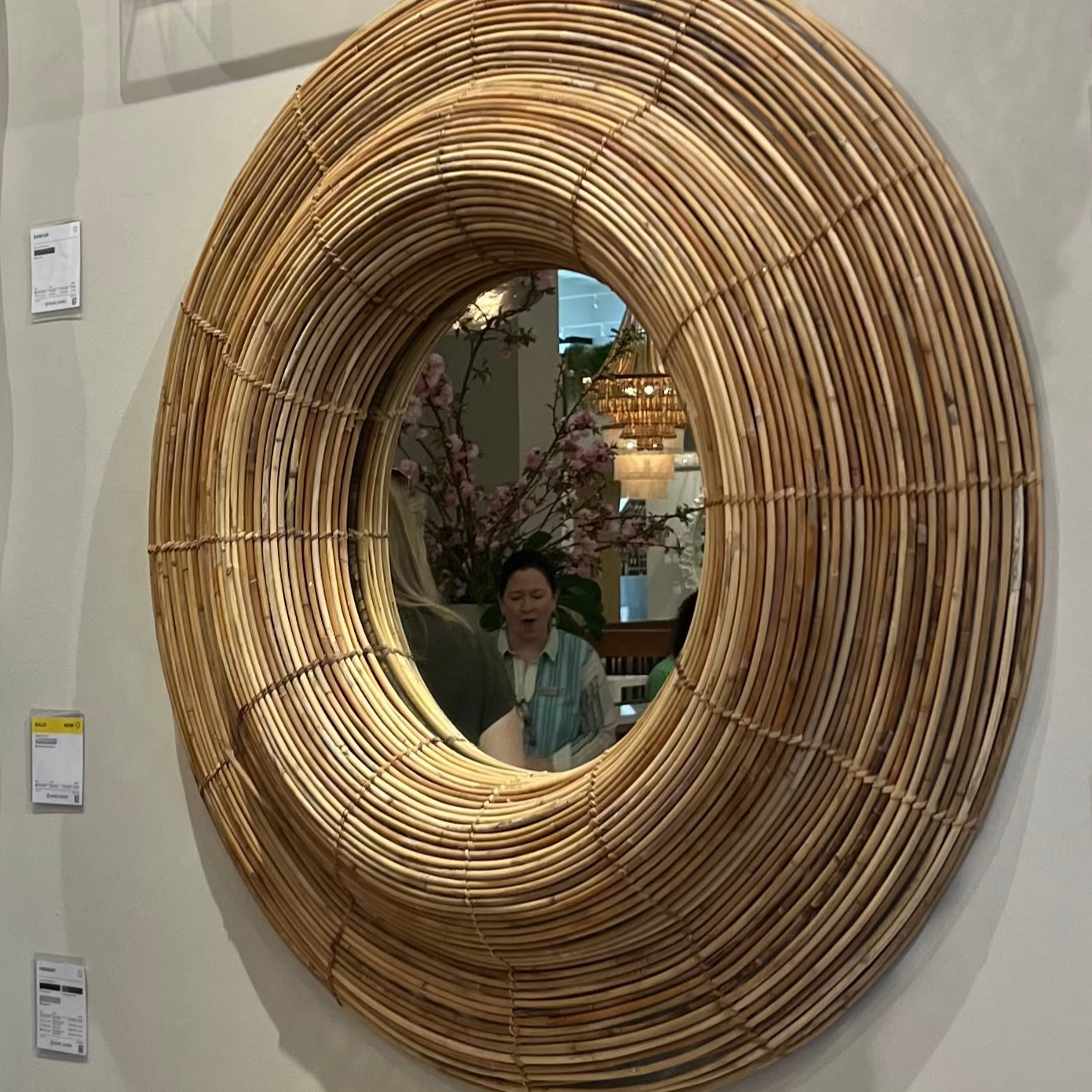 Round woven mirror on a wall with price tags