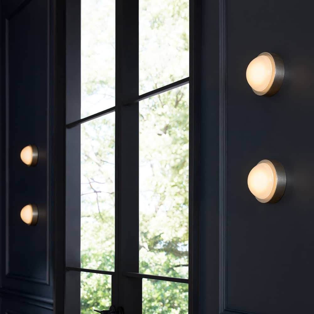 Modern wall lights on a dark wall with a window in the background