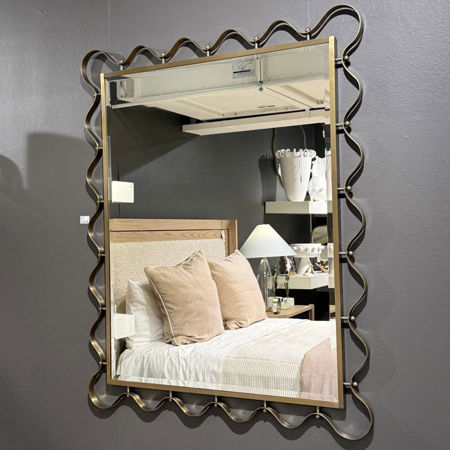 Decorative wall mirror with wavy frame on a gray wall