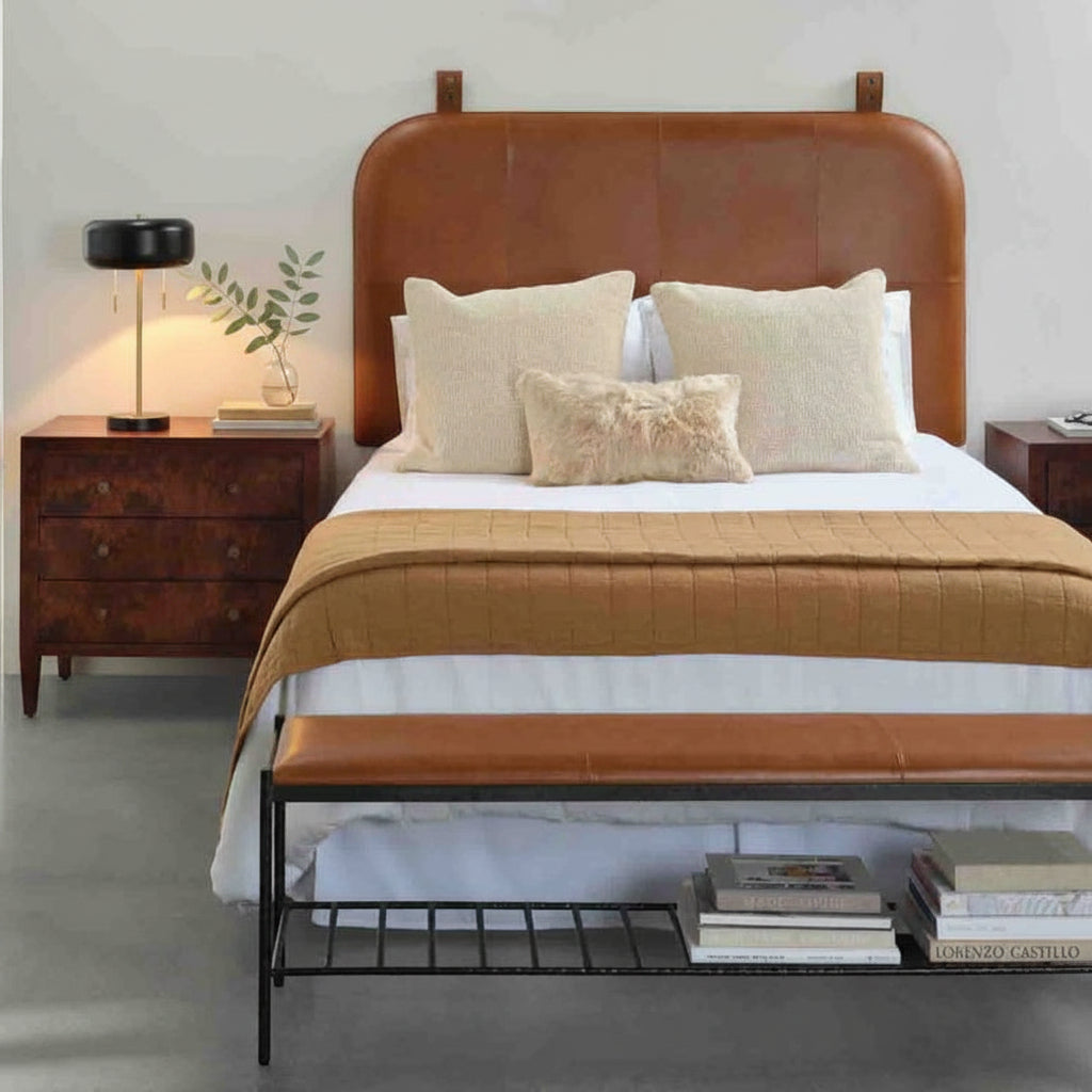 Bedroom with a brown leather headboard and matching bench, white bedding, and wooden nightstands.