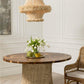 Round wooden table with decorative items in a room with wainscoting and a wicker chair.