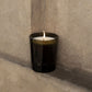 Black candle with a flame on a concrete surface