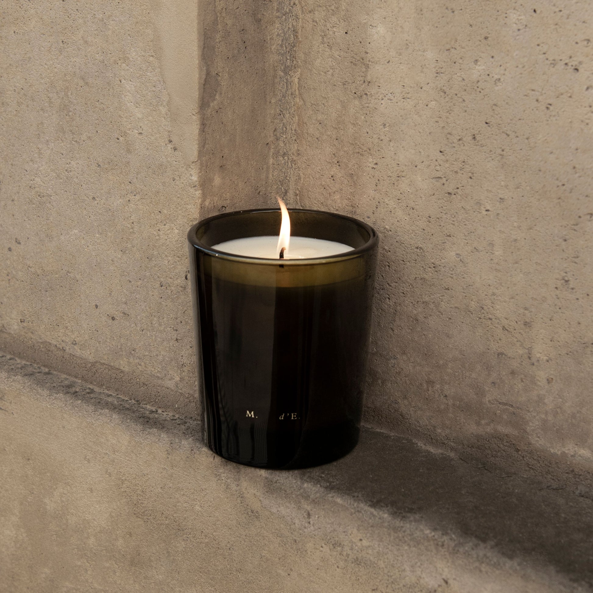 Black candle with a flame on a concrete surface