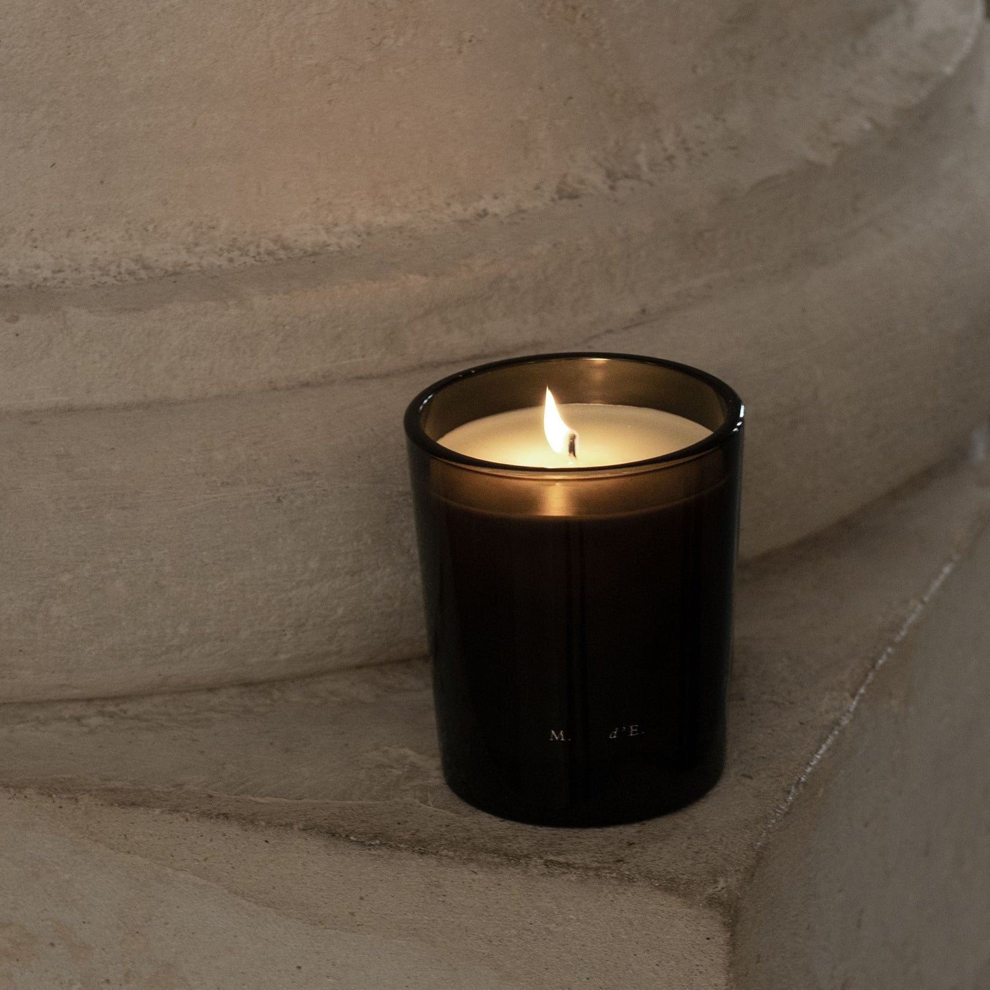 Black candle in a glass holder on a stone surface