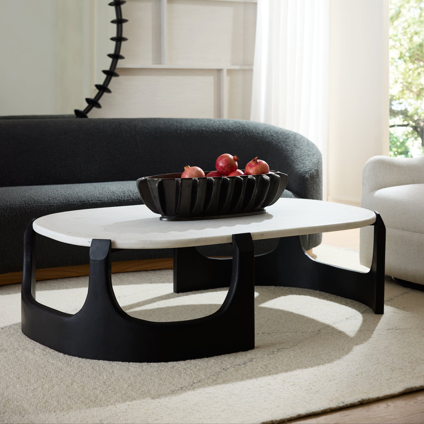 Modern living room with a black and white coffee table, gray sofa, and decorative elements.