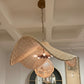 Woven pendant light hanging from a ceiling in a room with mirrors and lights.