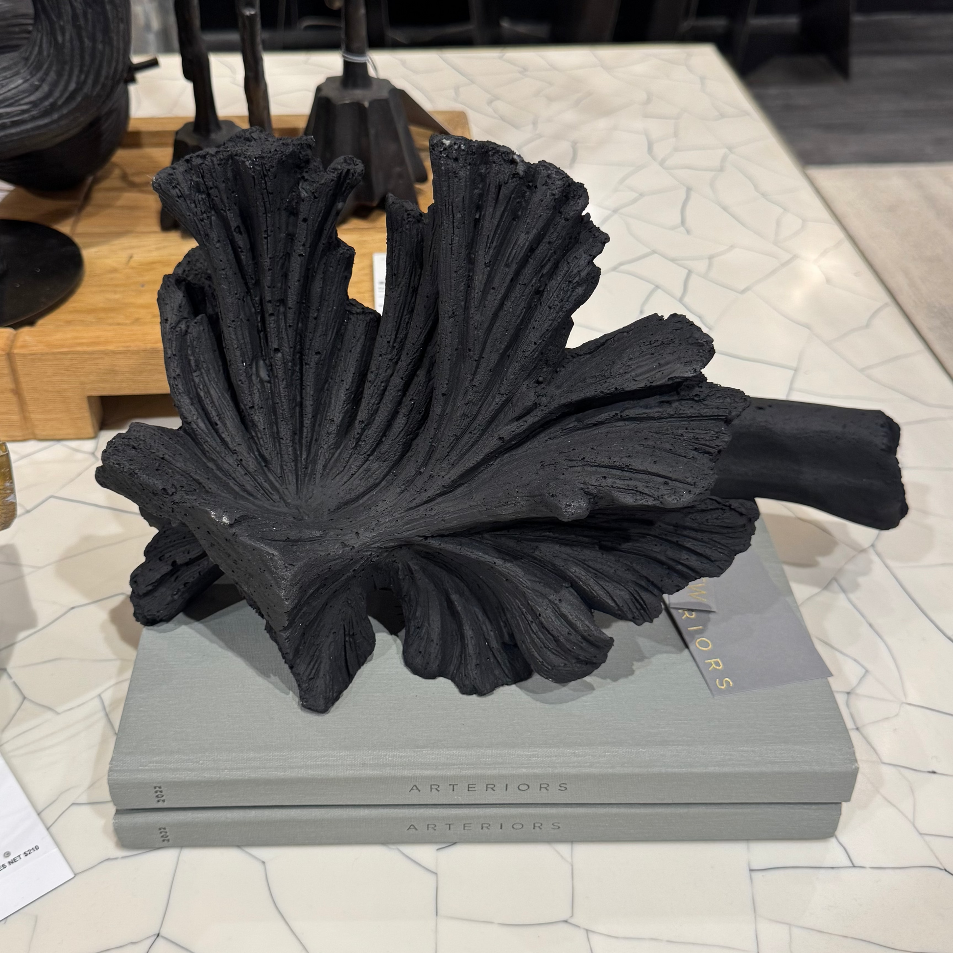 Decorative black sculpture on a gray platform with a tag in a store setting