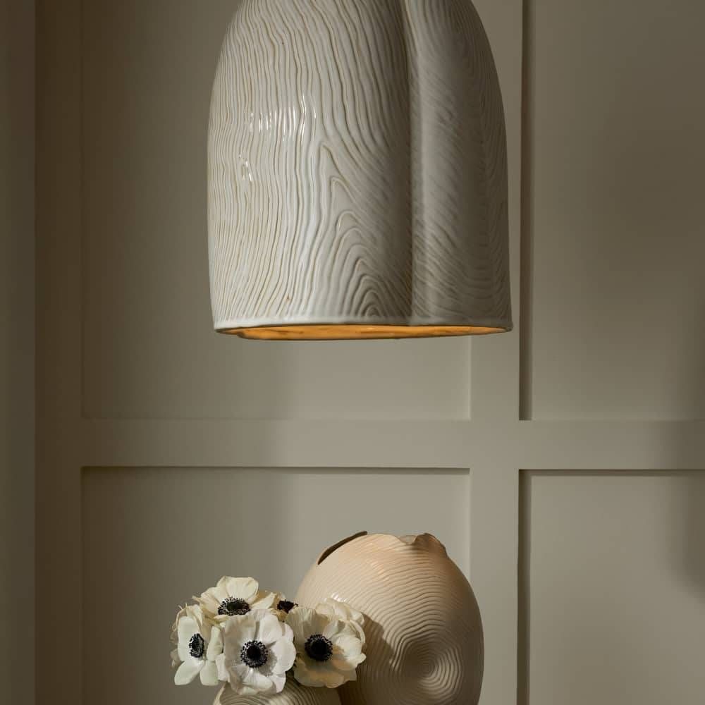 Decorative ceramic lamp with textured design on a neutral wall.