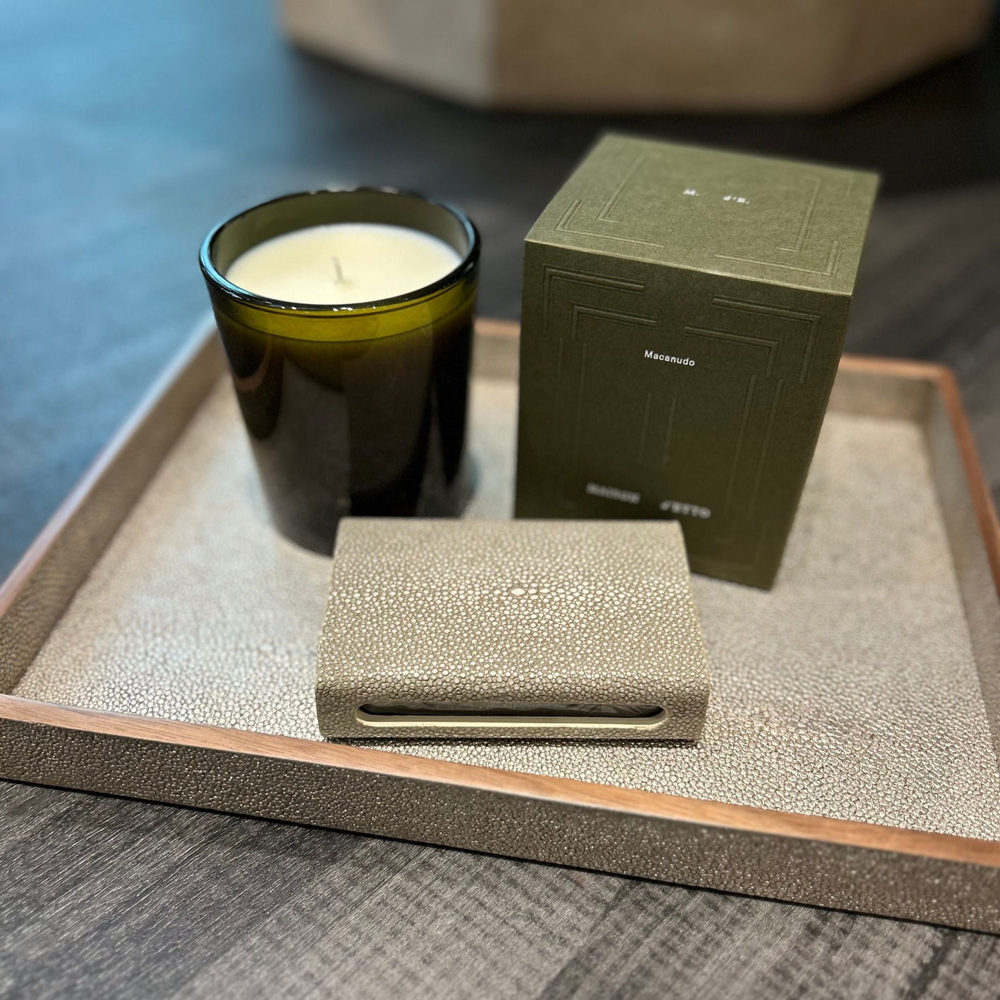 Candle, box, and shagreen case on a textured surface