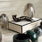 Decorative black sculpture on a white box with marble-like objects in a stylish interior setting.