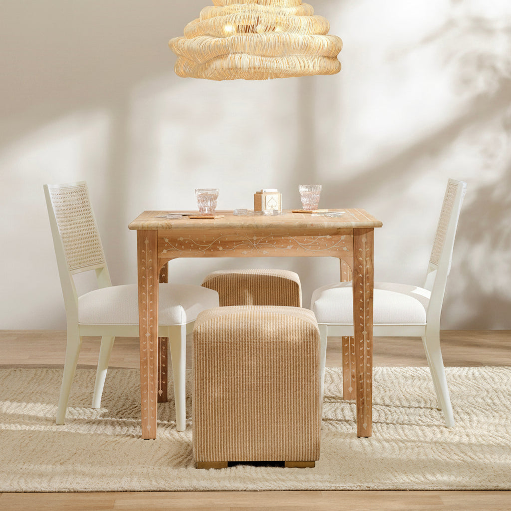 Dining area with wooden table, chairs, and ottoman under a pendant light.