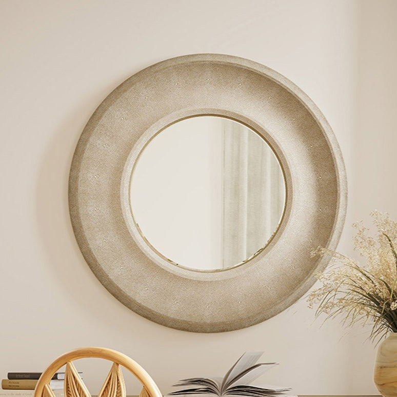 Wooden desk with a chair and decorative items in a room with a round mirror on the wall.