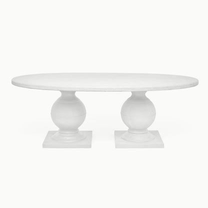 An oval dining table with a white plaster top and a pedestal base, designed for outdoor use.