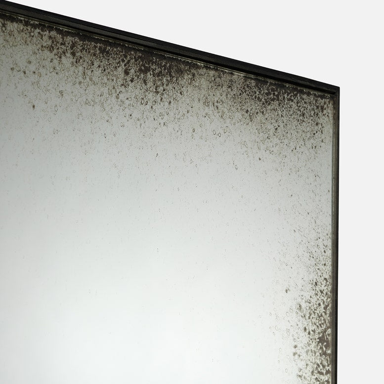 Close-up of a mirror with black mold growth on a white background