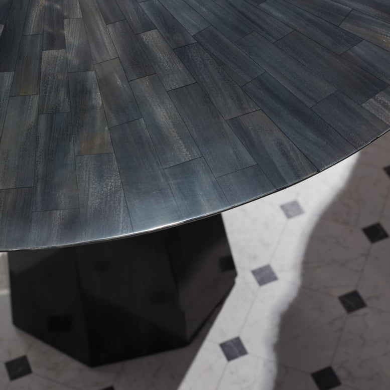 Close-up of a dark wooden table with a herringbone pattern on a tiled floor.