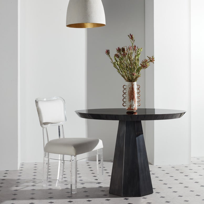 Modern dining table with a vase of flowers and a chair in a minimalistic room.