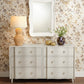 White dresser with decorative items against a patterned wall